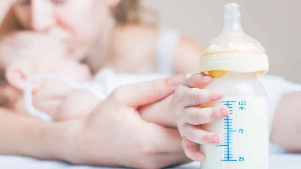 Baby holding a bottle of infant formula.