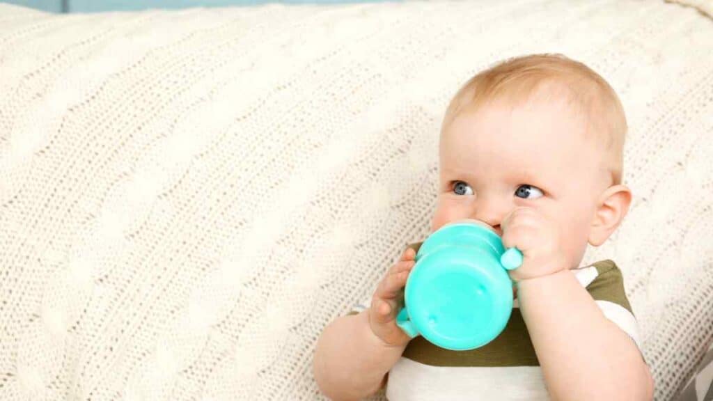 baby drinks in green sippy cup