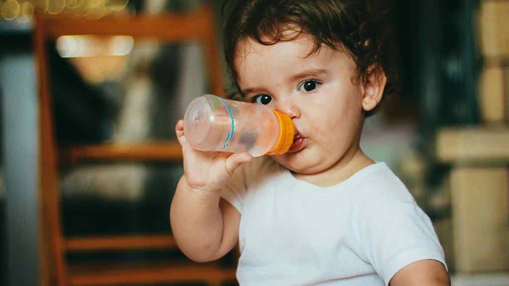 baby drinks in a small bottled water