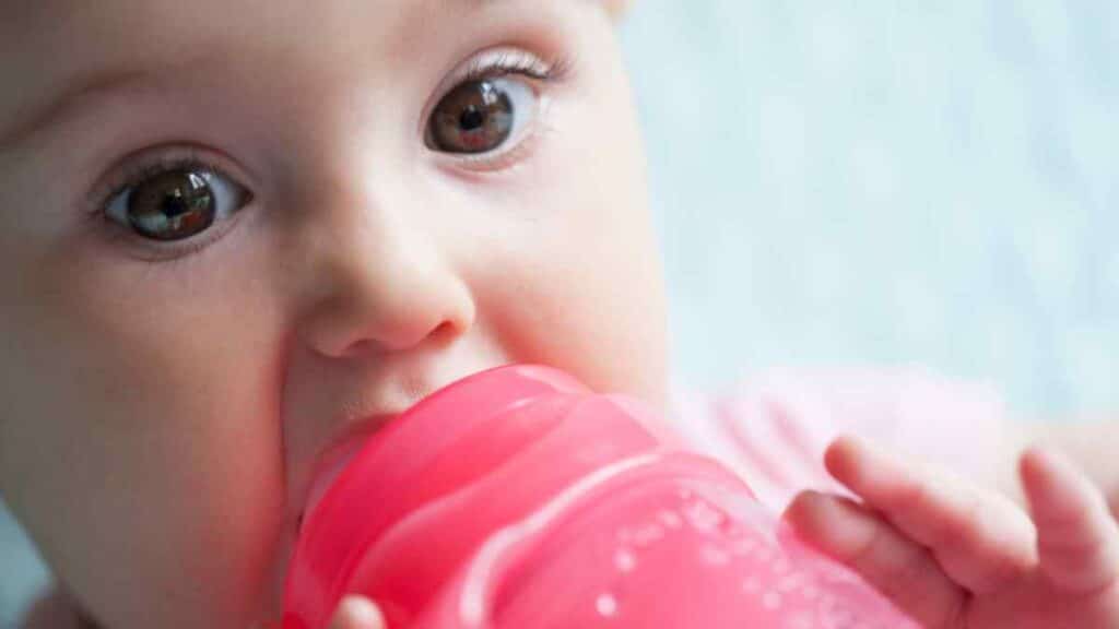Baby drinks in red sippy cup. 