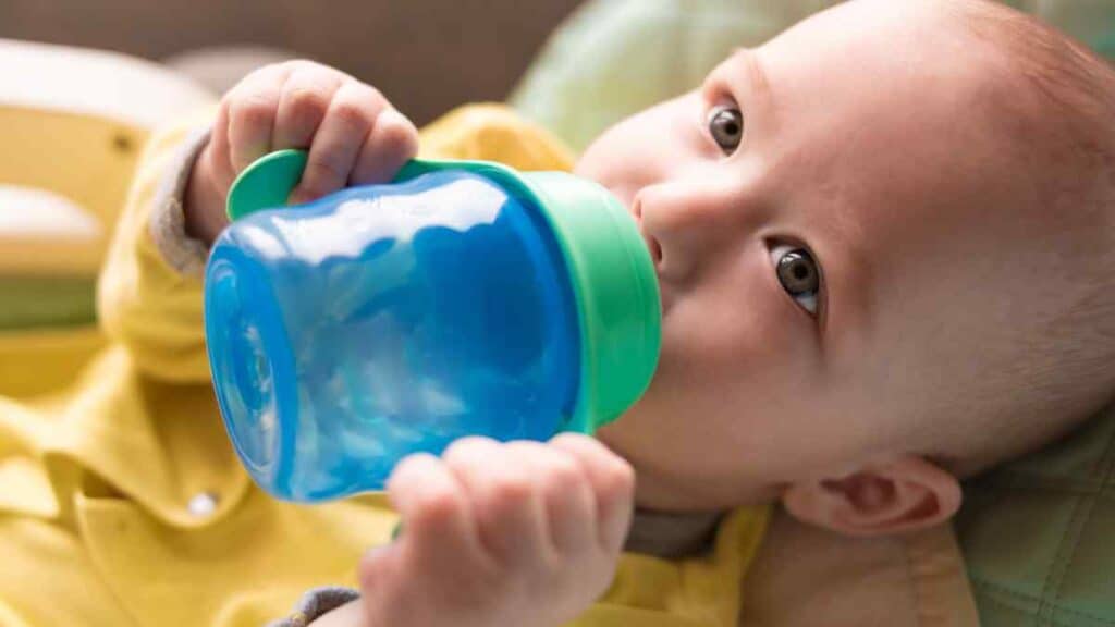 baby drinks in blue sippy cup.