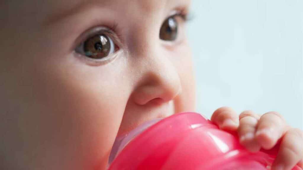 baby drinks in red bottle