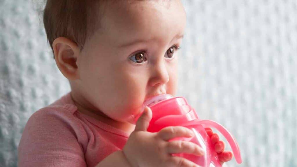 Baby drinks in red sippy cup.