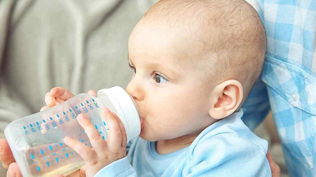 Baby drinks in baby bottle.