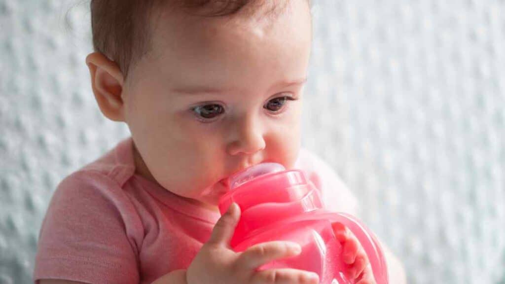 Baby drinking in red sippy cup.