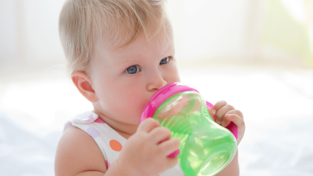 baby using green sippy cup