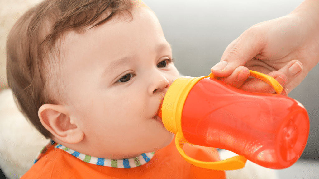 baby uses orange sippy cup